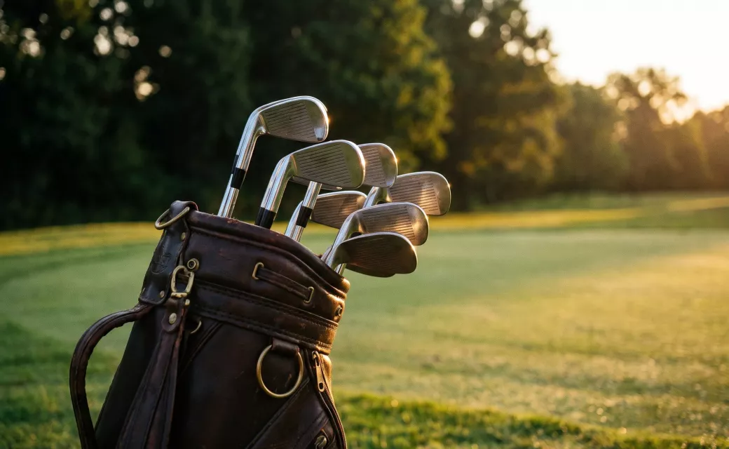 Sac de golf en cuir avec une série de fers et de wedges au bord du fairway